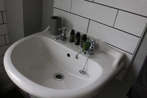 诺丁汉Charming 2 Bed House - Family Friendly的浴室内的一个白色水槽,里面装有瓶子