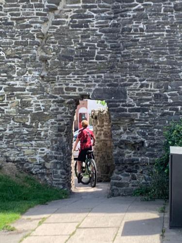 康威3 Newboro Terrace, Conwy的骑着自行车穿过石墙的人
