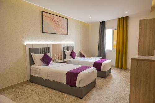 麦地那فندق زوايا الماسية فرع الحزام的酒店客房配有两张带紫色枕头的床