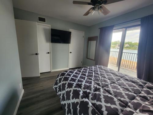 欧塞奇比奇Lakefront condo with a VIEW Osage Beach的一间卧室配有一张床、一台电视和一个阳台