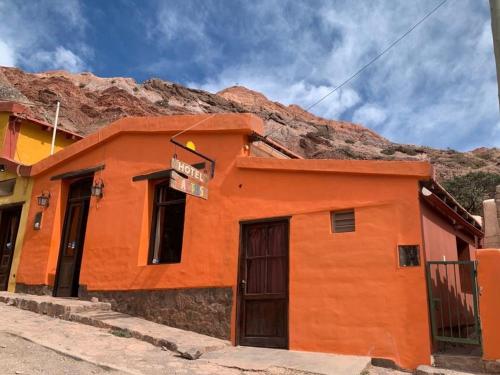 普尔马马尔卡Hotel Cactus Cerro的一座橙色的建筑,在山前