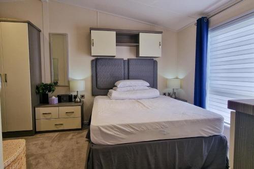 亨斯坦顿Stunning 6 Berth Lodge With Decking At Manor Park In Hunstanton Ref 23064k的一间卧室配有带白色床单和枕头的床。