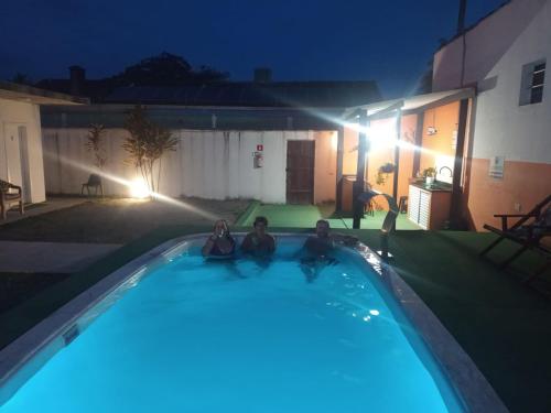 瓜鲁雅Suíte Luxo Refúgio das Ostras的两人晚上坐在游泳池里