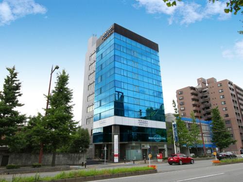 福冈新盖亚多梅玛耶酒店的一座高大的玻璃建筑,前面有一辆红色的汽车
