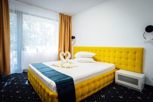 马马亚Hotel & MedSpa Siret的一张床上,有一个黄色床头板