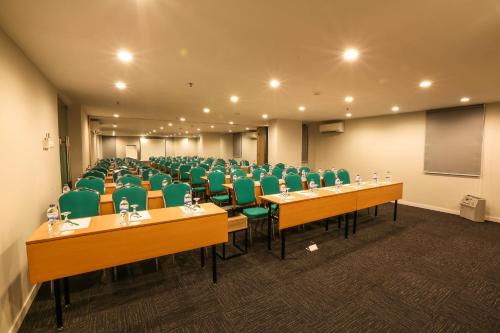 日惹Hotel Citradream Tugu Yogyakarta的一间会议室,配有书桌和绿色椅子