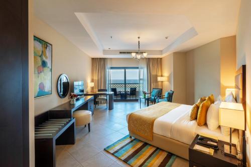 富查伊拉Al Bahar Hotel & Resort的配有一张床和一张书桌的酒店客房