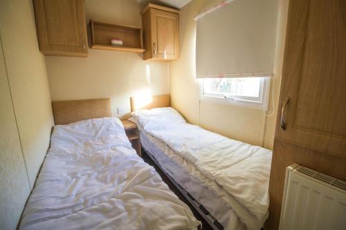 亨斯坦顿Caravan With Decking At Manor Park In Hunstanton, Sleeps 6 Ref 23045b的小房间设有两张床和窗户