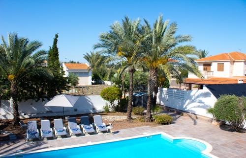 拉纳卡Villa Artemis的一个带椅子的游泳池,棕榈树