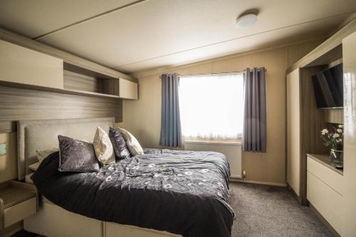 大雅茅斯Modern 6 Berth Caravan With Decking At Cherry Tree Park In Norfolk Ref 70324c的一间卧室设有一张大床和窗户