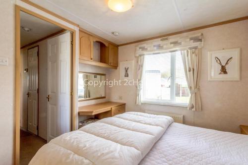 亨斯坦顿Stunning 6 Berth Caravan At Manor Park In Hunstanton Norfolk Ref 23194k的卧室设有一张白色大床和一扇窗户。