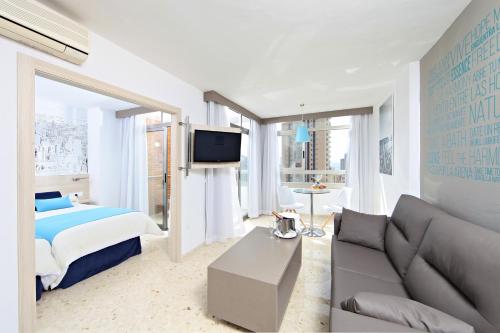贝尼多姆Flamingo Beach Resort - Adults Recommended的一间卧室配有一张床、一张沙发和一台电视。