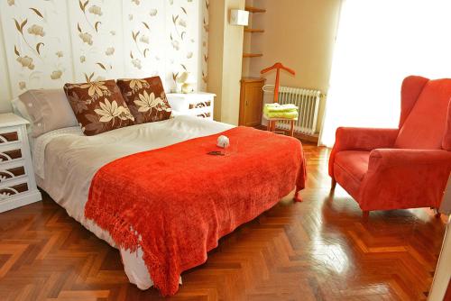 圣地亚哥－德孔波斯特拉Cruxa Apartments garaje incluido的一间卧室配有一张带红色毯子和椅子的床