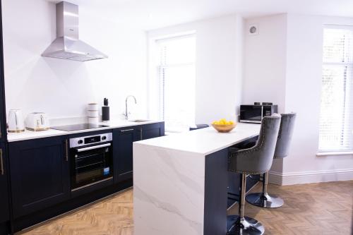 卡迪夫Designer Cardiff Apartments的厨房配有黑色橱柜和白色台面