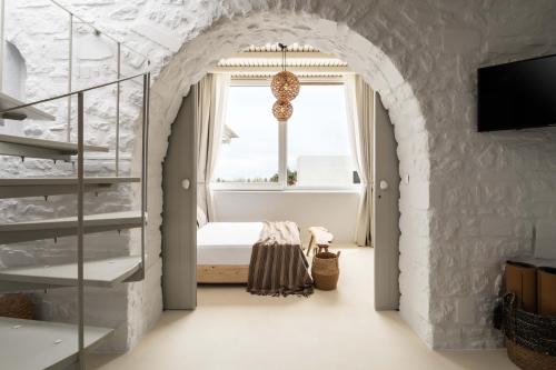 艾丽奇Cavos Paros Boho Chic sea-view apartment in Aliki的卧室设有拱门、一张床和一个窗户