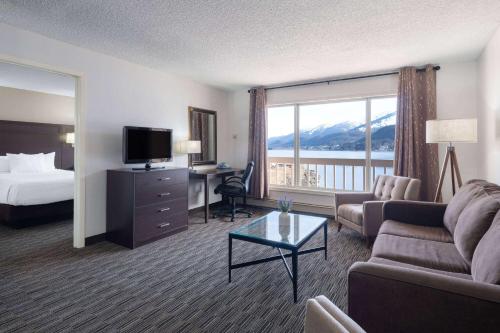 朱诺Ramada by Wyndham Juneau的酒店客房配有床、沙发和电视。