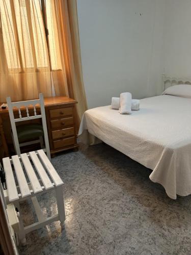 卡沃内拉斯Pensión Las Palmas的一间卧室配有一张床、一把椅子和一张书桌