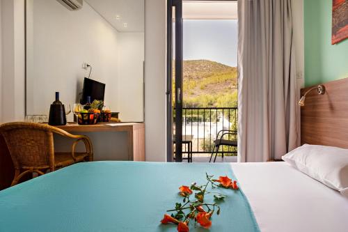 波罗斯Hotel Pavlou的一间卧室配有一张带蓝色桌子和鲜花的床