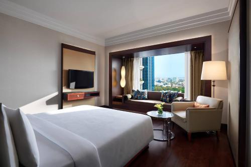 班加罗尔JW班加罗尔万豪酒店的酒店客房配有床、沙发和电视。