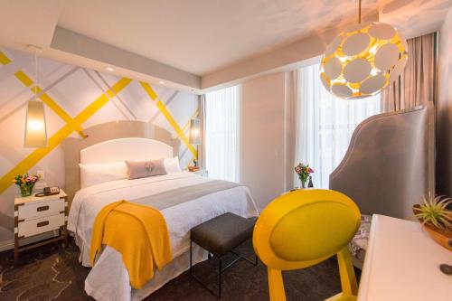 伯明翰Elyton Hotel, Autograph Collection的一间卧室配有一张床和一张黄色椅子