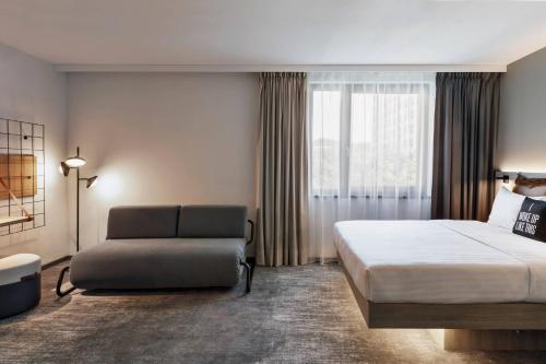 汉堡Moxy Hamburg City的一间卧室配有一张床、一张沙发和一个窗口