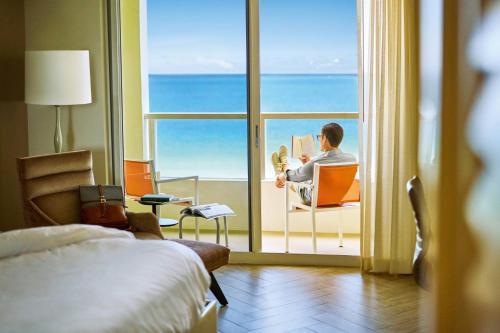 迈阿密海滩斯坦顿南海滩万豪酒店的坐在椅子上看书的人在窗前