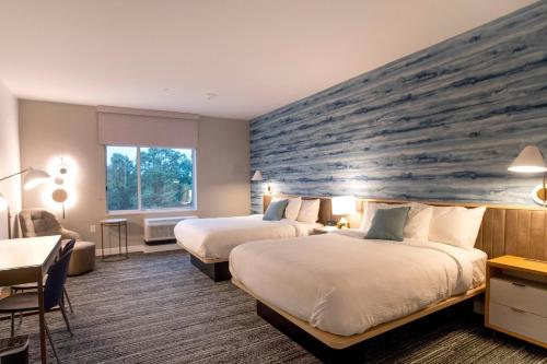 孔洛TownePlace Suites by Marriott Conroe的酒店客房带两张床和一个大石墙