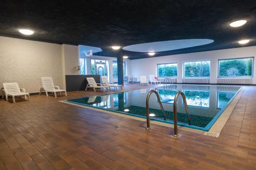 罗恩佐Hotel Regina del Bosco的游泳池,带椅子的房间和游泳池