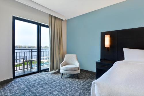 沃尔顿堡滩Residence Inn by Marriott Fort Walton Beach的一间带一张床和一把椅子的卧室以及一个阳台