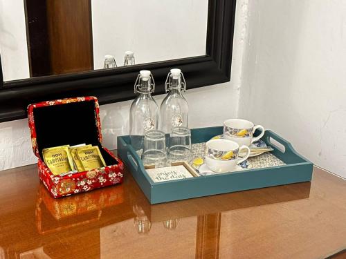 马六甲19th Century Boutique Hotel的盘子上放了两瓶和杯子
