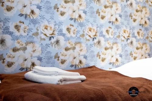 库特诺CukroVia的一张带毛巾和花卉壁纸的床