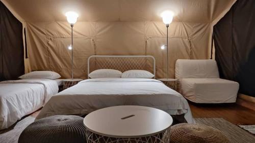 新山Canopy Villa Sireh Park的帐篷配有两张床、一张桌子和一把椅子