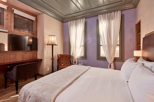 干尼亚多慕斯瑞尼尔精品 - 全球历史酒店的一间卧室配有一张床、一张书桌和一台电视