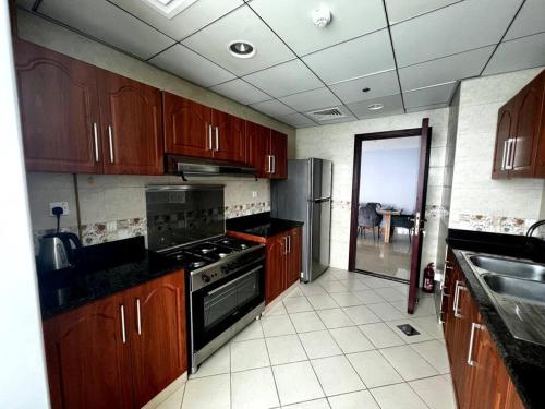 阿吉曼Luxury full sea view flat的厨房配有木制橱柜和炉灶烤箱。