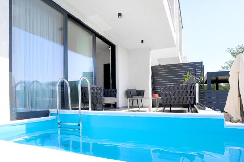 奈维斯Apartments Terra Sun with Private Pool or Jacuzzi的一个带两把椅子的游泳池以及一座房子