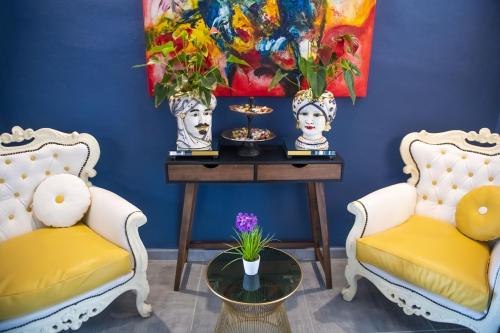 费拉拉Boutique Hotel Ferrara的蓝色的客房配有两把椅子和一张带鲜花的桌子