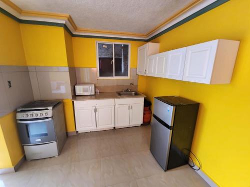 Super Two Bedroom Penthouse in Peguy-Ville的一间设有黄色墙壁和白色橱柜的小厨房
