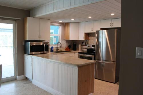 夏洛特港Pool house in Port Charlotte的厨房配有白色橱柜和不锈钢冰箱
