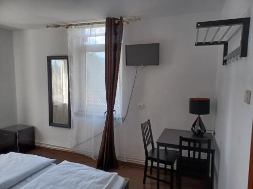普雷代亚尔Vila Oltețul的一间卧室配有一张床、一张桌子和一个窗户。