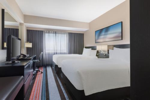 皇后区纽约肯尼迪机场万怡酒店的酒店客房设有两张床和一台平面电视。
