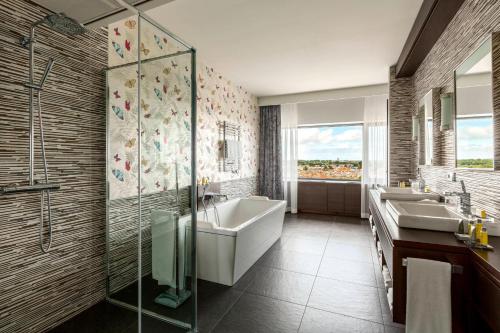海牙海牙万豪酒店的浴室配有2个盥洗盆、浴缸和淋浴。