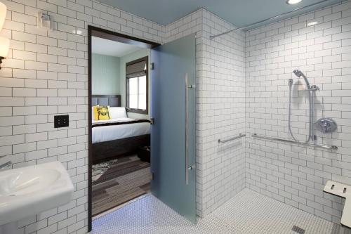 圣巴巴拉Moxy Santa Barbara的带淋浴和盥洗盆的浴室以及1张床。