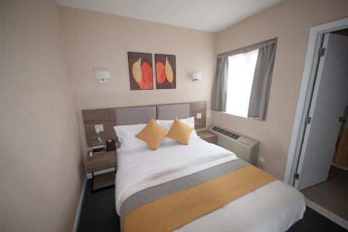 皇后区Flushing Garden Hotel的一间卧室配有带白色床单和黄色枕头的床。