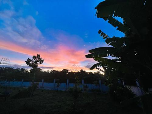 怡保Lanai Meranti的落在有树和栅栏的田野上的日落