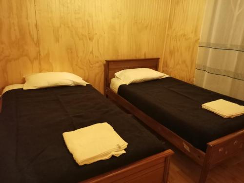 洛斯安赫莱斯Cabañas Candelaria的配有两张床铺的客房内配有黑色床单和白色毛巾