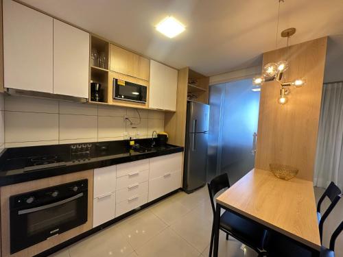 戈亚尼亚Apartamento Luxo St Bueno的厨房配有白色橱柜和木桌