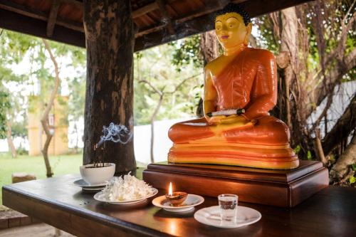 蒂瑟默哈拉默Thaulle Pure Ayurveda Resort - Yala的坐在桌子上,用蜡烛装饰的佛陀雕像