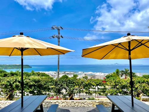 本部Resort & Villa RYUNON的两张带黄伞的野餐桌,位于海洋前