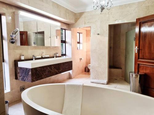 哈特比斯普特The Villa Luxe Hartbeespoort Spacious Golf & Wildlife Estate的带浴缸、水槽和镜子的浴室