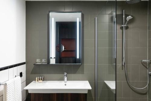 阿斯米尔Renaissance Amsterdam Schiphol Airport Hotel的浴室配有盥洗盆和带镜子的淋浴